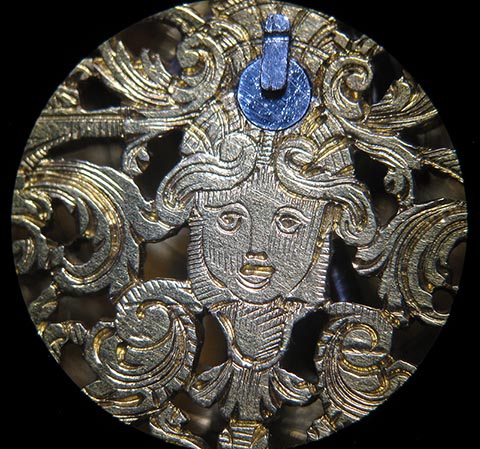 Antike Tischuhr mit Spindelhemmung, angetrieben durch Fusee (Schnecke) und Kette. Detail eines Motivs der skelettierten Unruhbrücke.