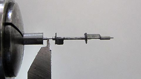 Herstellung des Zapfens mit Welle der Unruhachse auf der Drehmaschine. Antike Tischuhr mit Spindelhemmung, angetrieben durch Fusee und Kette.