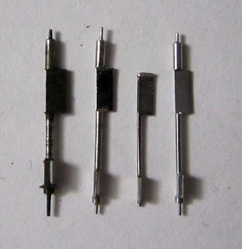 Herstellung der Unruhachse. Drei gefertigte Unruhwellen mit gerader Palettenseite neben der gebrochenen. Antike Tischuhr mit Spindelhemmung.