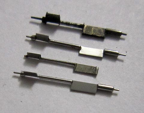 Antike Tischuhr mit Spindelhemmung. Herstellung der Unruhachse. Drei gefertigte Unruhwellen neben der gebrochenen. Seitenansicht.