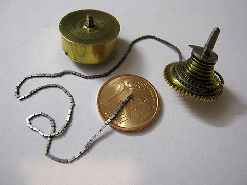 Gesamtansicht der Schnecke (Fusée) und der Galle-Kette. Der gefertigte Haken liegt zum Größenvergleich auf einer Zwei-Cent-Münze. Antike Tischuhr mit Spindelhemmung.